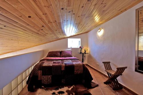 a bed in a room with a wooden ceiling at Quintal do Castelo in Silves