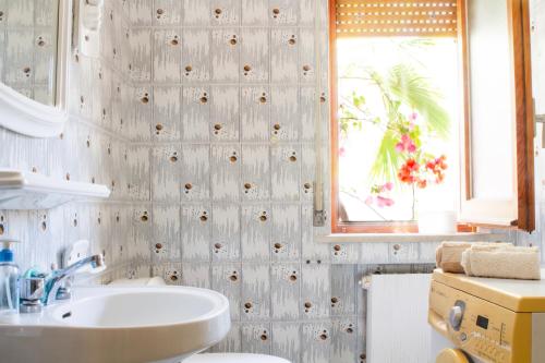 łazienka z białą umywalką i oknem w obiekcie Grande appartamento sul lungomare a Villa Rosa (TE) w miejscowości Alba Adriatica