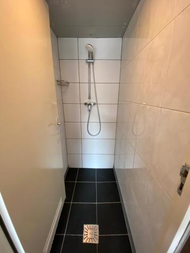 a bathroom with a shower with a black tile floor at Hostel Utopia in Amsterdam