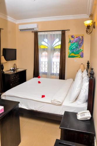a bedroom with a large white bed with a window at Golden Tulip Stone Town Boutique in Zanzibar City