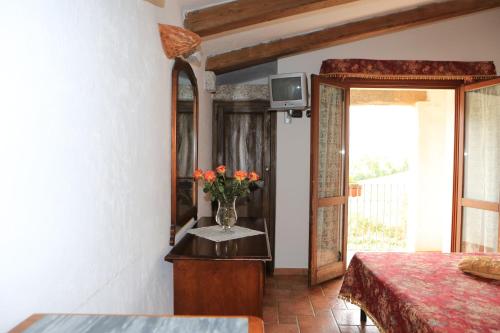 1 dormitorio con un jarrón de flores sobre una mesa en Agriturismo Vermentino, en Monti