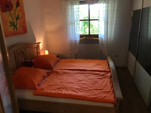 a bedroom with a bed with orange sheets and a window at Ferienwohnung Evi in Auerbach