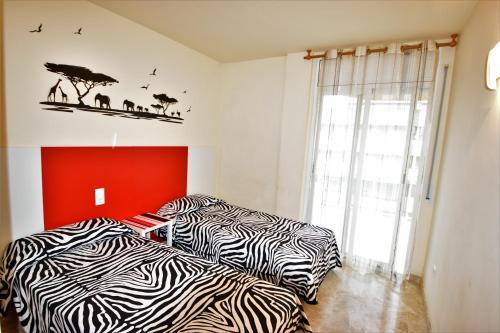 1 dormitorio con 2 camas y pared roja en Ventura Park A-6, en Salou