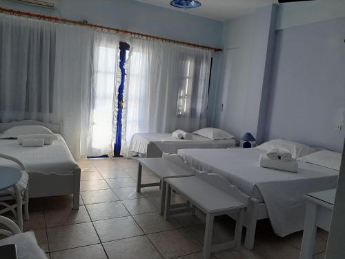 a room with three beds and tables and a window at Villa Nefeli in Perissa