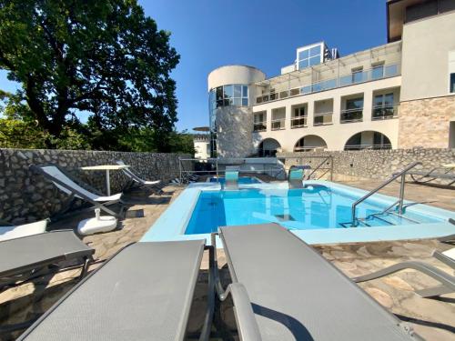 a swimming pool with chairs and a building at Bástya Konferencia és Wellness Hotel in Miskolctapolca