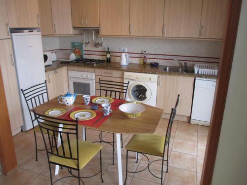 een keuken met een houten tafel met stoelen en een keuken met een fornuis bij Casa Carmela in Burgau