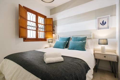 1 dormitorio con 1 cama grande con almohadas azules en Magno Apartments Encarnación, en Sevilla