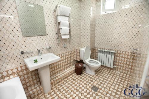 a bathroom with a toilet and a sink and a mirror at GG Group Hotel in Almaty