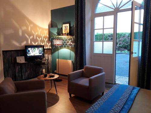 ein Wohnzimmer mit einem Sofa, einem Stuhl und einem TV in der Unterkunft Les Tulipiers, Parking Sécurisé, Lit Queen-Size, Palais des Congrès in Le Mans