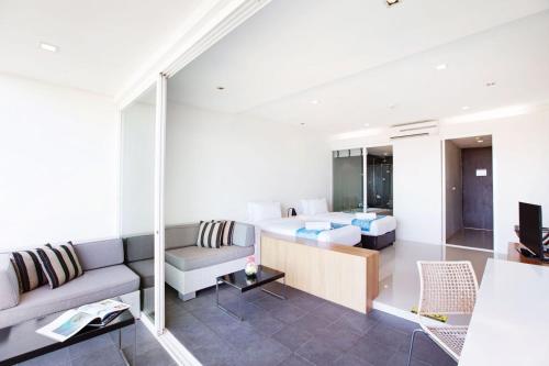 a living room with a couch and a bed in a room at Mida De Sea Hua Hin - SHA PLUS in Cha Am