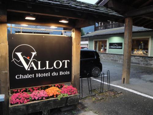a sign for a hotel with flowers in a parking lot at Chalet Hôtel du Bois in Les Houches