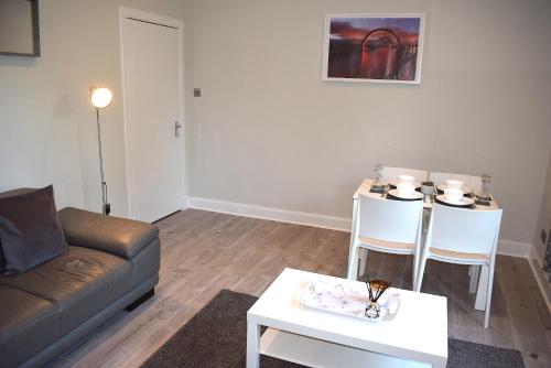 
a living room with a couch and a table at Kelpies Serviced Apartments- Victoria in Falkirk
