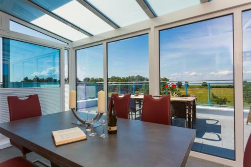 a dining room with a table and chairs and large windows at Appartementhäuser Achterwasserblick in Ostseebad Koserow