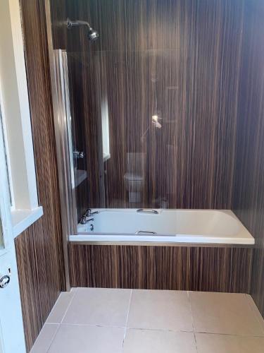 a bathroom with a bath tub with wooden walls at Cathedral Hotels Norwich in Norwich