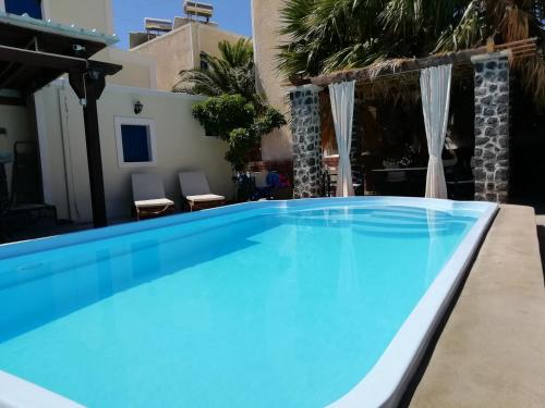 a large blue swimming pool in a yard with two chairs at 5bedroom villa in perissa beach in Perissa