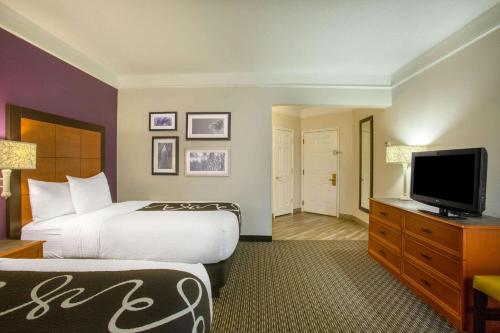 a hotel room with a bed and a flat screen tv at La Quinta by Wyndham St. Louis Westport in Saint Louis