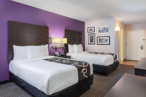 two beds in a hotel room with purple walls at La Quinta by Wyndham Clifton/Rutherford in Clifton