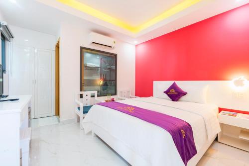 a bedroom with a white bed and a red wall at Sen Hotel Phu Quoc in Phu Quoc