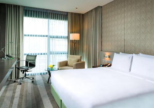 a hotel room with a large white bed and a desk at Holiday Inn Bangkok Sukhumvit by IHG in Bangkok
