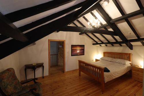 a bedroom with a bed and a chair at Bryngolau in Brechfa
