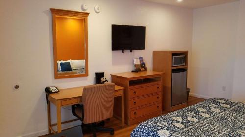 a bedroom with a desk and a bed and a desk with a computer at Rodeway Inn Alameda-Oakland in Alameda