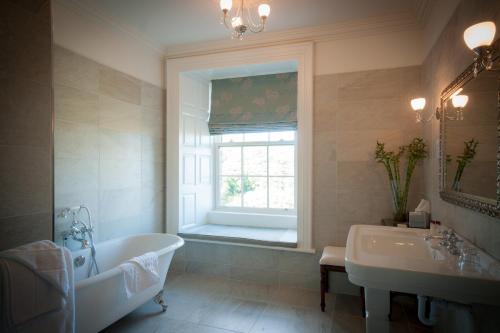 a bathroom with a tub and a sink and a window at Falls Hotel & Spa in Ennistymon