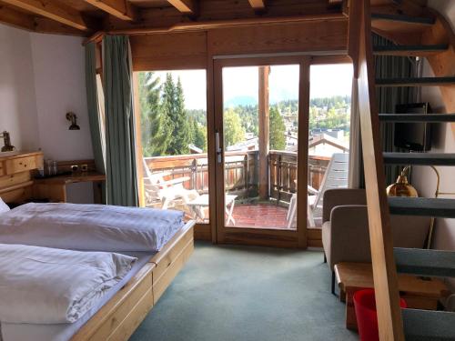 a bedroom with a bed and a balcony with a view at Arena Guesthouse in Flims