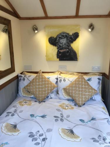 una cama con una foto de una vaca en la pared en Waterloo Farm Shepherds Hut Glamping en Perth