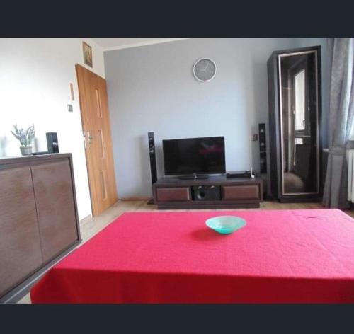 uma sala de estar com uma mesa vermelha e uma televisão em Apart Bella em Uniejow