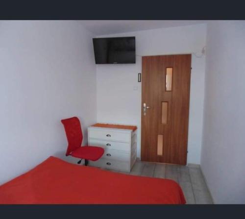 1 dormitorio con cama roja y silla roja en Apart Bella en Uniejow