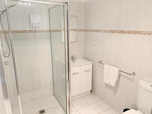 a white bathroom with a shower and a toilet at City Center - Comfortable 2-Bedroom Apartment in Armidale