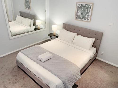 a bedroom with a large white bed with two mirrors at City Center - Comfortable 2-Bedroom Apartment in Armidale