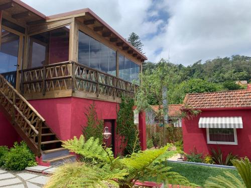 a red house with a balcony and a yard at Storytellers Villas in Sintra