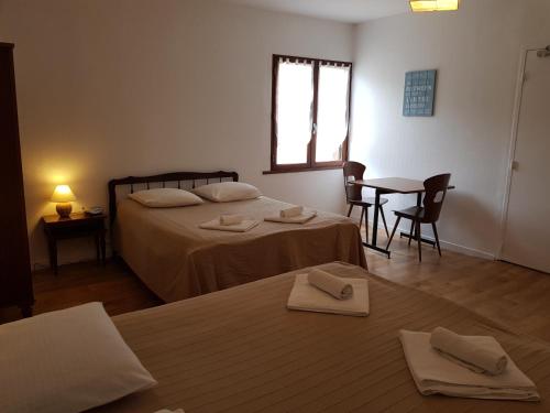 a bedroom with two beds and a table and a window at Acacias Hôtel Motel in Vendays-Montalivet