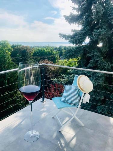 a glass of wine sitting next to a chair on a balcony at Mirador Balaton design Villa in Balatonakarattya