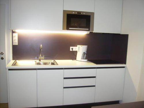 a white kitchen with a sink and a microwave at Appartements Christa in Dobbiaco