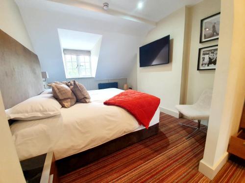 a bedroom with a bed and a tv on the wall at Hartnoll Hotel & Spa in Tiverton