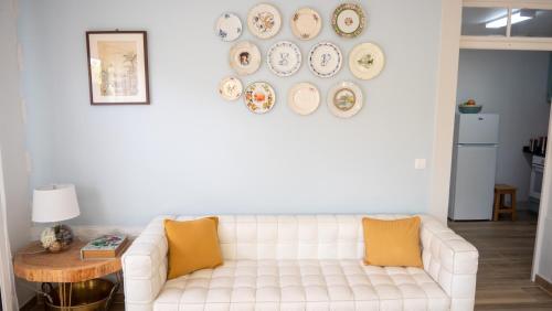 a living room with a white couch and plates on the wall at Casa da Bungavillia in Machico