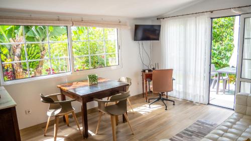 a dining room with a table and chairs and windows at Casa da Bungavillia in Machico