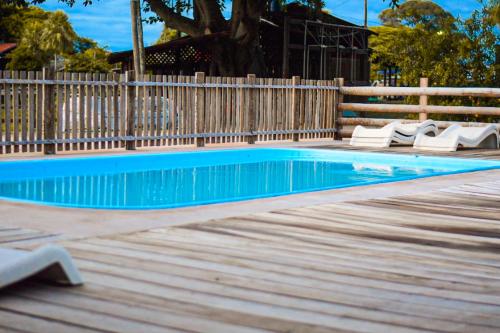 a swimming pool with chairs and a wooden fence at Pousada São João - Estrada Parque Pantanal in Corumbá