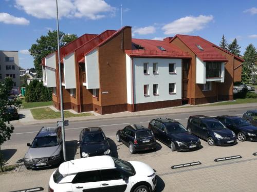 eine Gruppe von Autos, die auf einem Parkplatz vor einem Haus geparkt sind in der Unterkunft Centro apartamentai in Birštonas