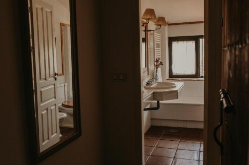 a bathroom with a sink and a toilet and a mirror at Hotel Posada de Valdezufre in Aracena
