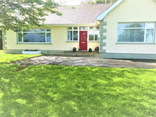 a house with a red door and a yard at Knocknagore Cottage in Gilford