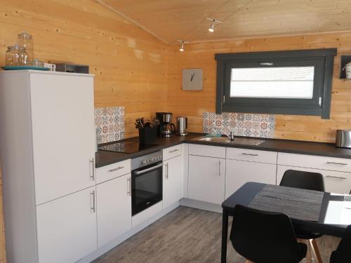 a kitchen with white cabinets and a table and a window at Holiday Home Ferienhaus Barbara by Interhome in Enspel