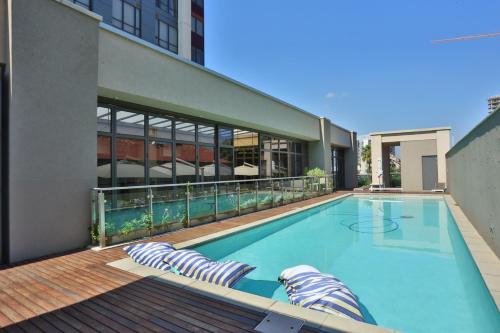 a swimming pool with lounge chairs in front of a building at 305 Sandton Skye in Johannesburg