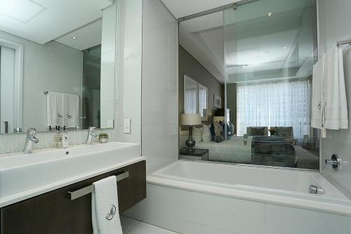 uma casa de banho branca com uma banheira e um espelho grande em 305 Sandton Skye em Joanesburgo