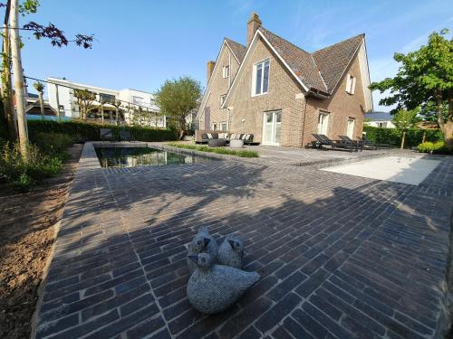 a house with a bird statue on a brick driveway at B&B Vis-à-Vis in Wenduine