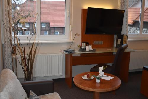 a living room with a desk and a tv at Hotel Neue Stuben in Wolfsburg