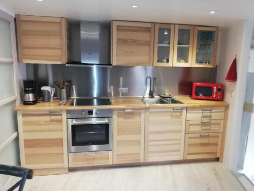 eine Küche mit Holzschränken, einer Spüle und einer Mikrowelle in der Unterkunft Honfleur-loft in Honfleur