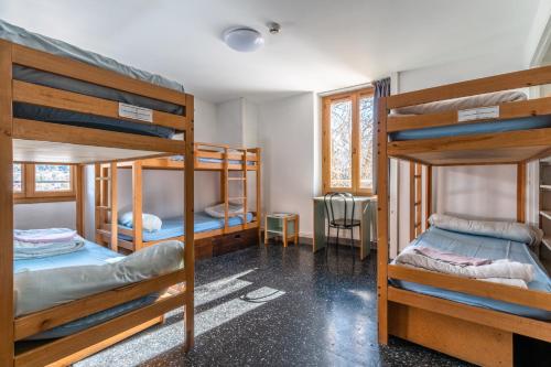 a dorm room with three bunk beds in it at Auberge de Jeunesse HI Serre-Chevalier in La Salle Les Alpes